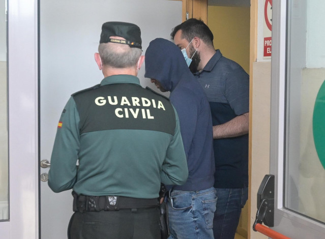 Dos agentes llevan al hombre detenido por haber agredido supuestamente a su pareja, para ser puesto en disposición judicial, en el Juzgado de Instrucción número 1, a 1 de junio de 2022, en Carballo, A Coruña, Galicia (España). El acusado propinó, presunta